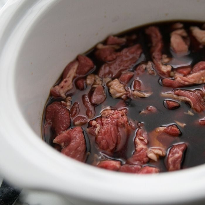 crockpot with beef and sauce inside for beef and broccoli