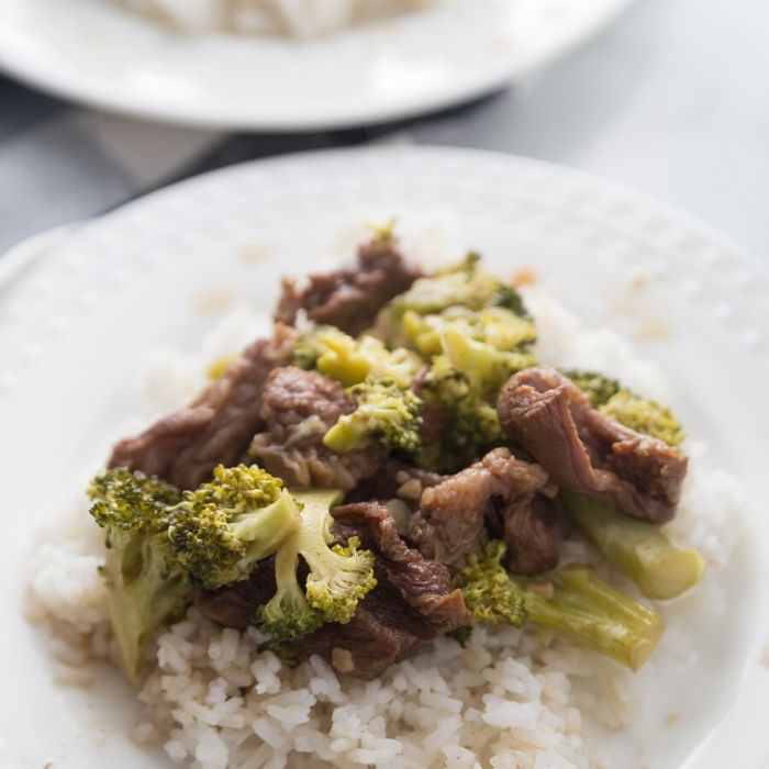 beef and broccoli with rice on a white plate on counter