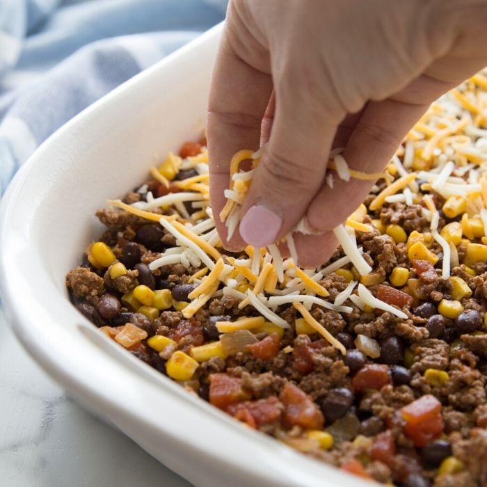 sprinkling cheese on taco bake casserole
