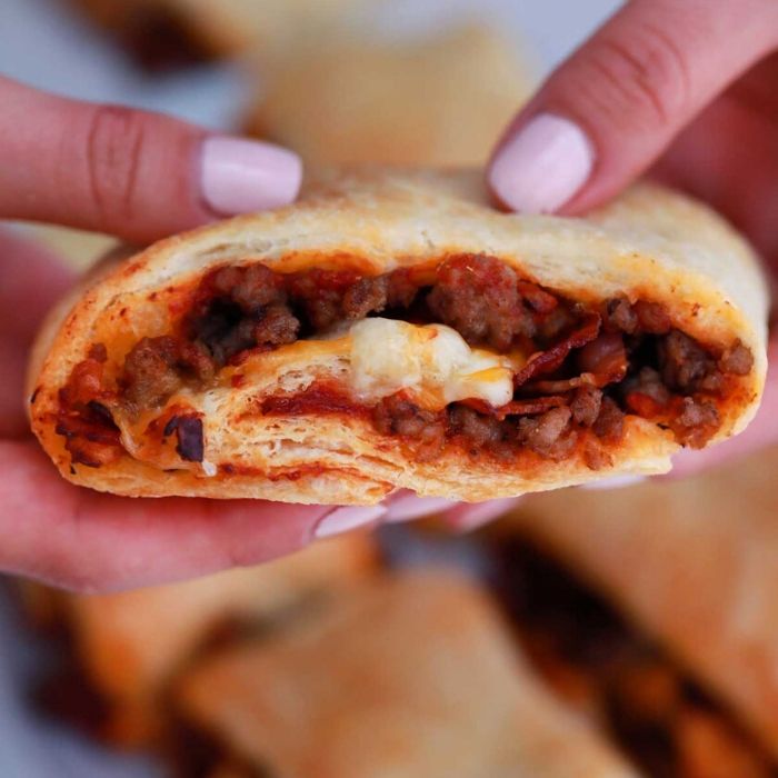 a person holding a bacon cheeseburger pinwheel in hands 
