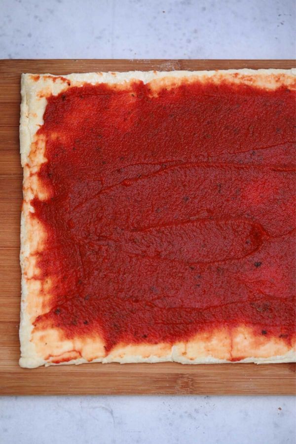 crescent roll pinwheels dough rolled out with sauce over the top