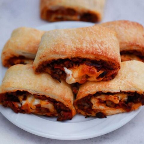 bacon cheeseburger pinwheels on a plate stacked up
