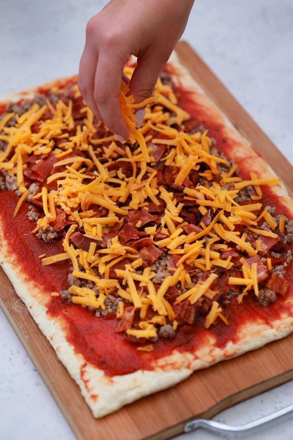 topping crecent roll dough with cheese and bacon 