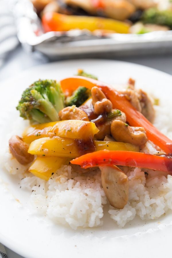 cashew chicken on a plate with rice underneath on plate