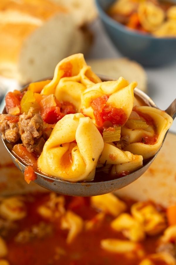 tortellini and sausage soup in a ladle 
