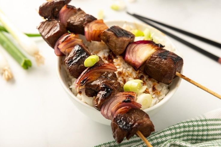 Skewers on top of a bowl with rice