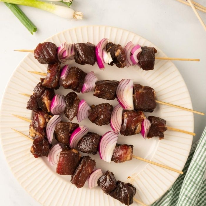 steak skewers on a plate on table 