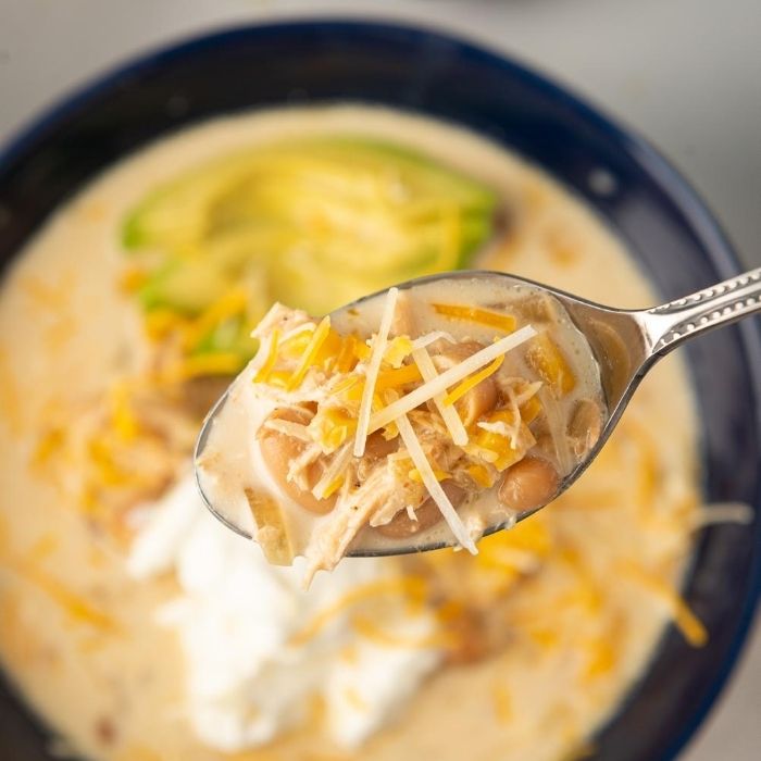 bowl of chicken chowder on spoon with cheese