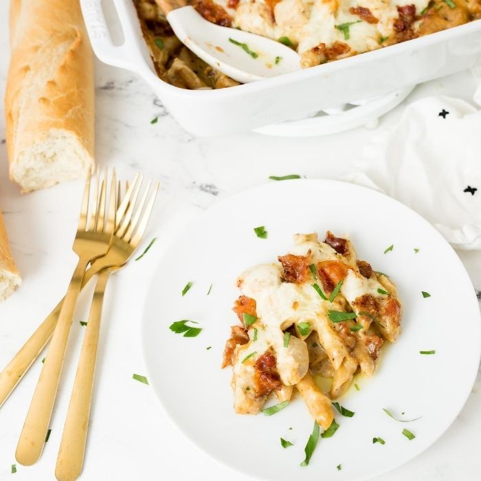 chicken pasta on a plate with gold silverware by it 
