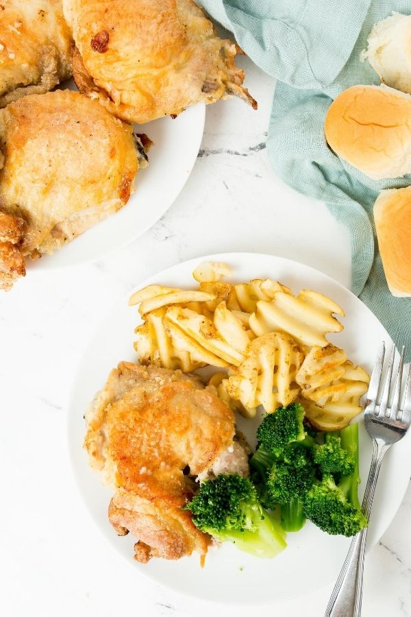 fried chicken on a plate with rolls by it 