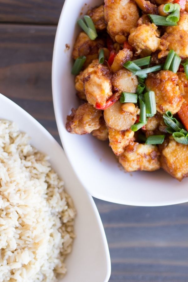 kung pao chicken in bowl with rice by it 