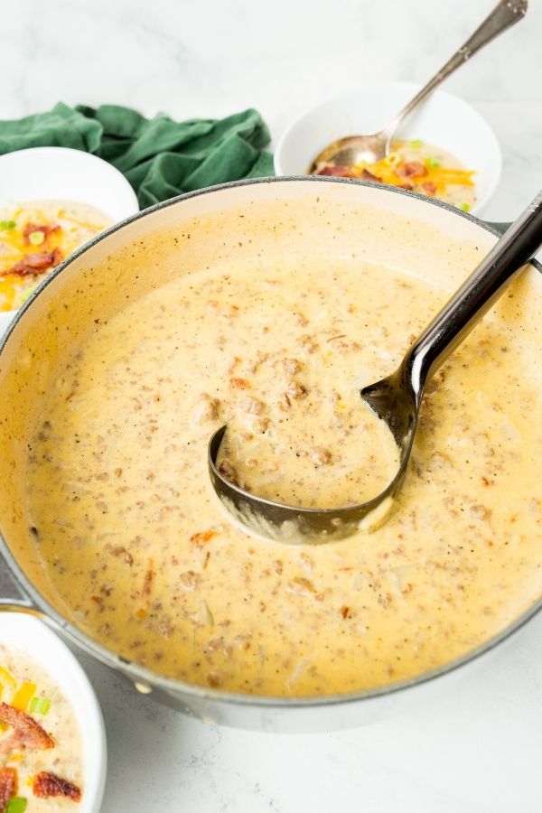 big pot of soup with ladle in it and bowls around it 