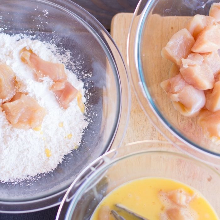 dredging chicken in egg and flour mixture 