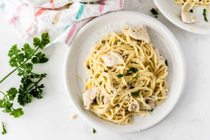 plate of chicken piccata and greens around the plate