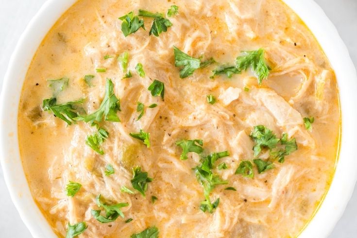 bowl of chicken green chili soup topped with greens