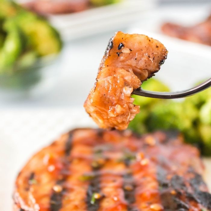 fork with some pork chop on it and plate underneat