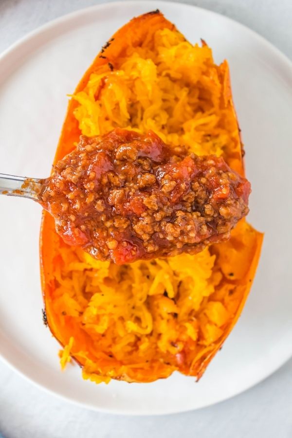 homemade pasta sauce on spoon above spaghetti squash