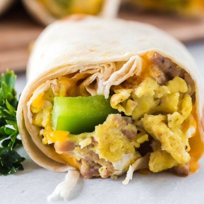 breakfast burrito on table with others stacked behind it 