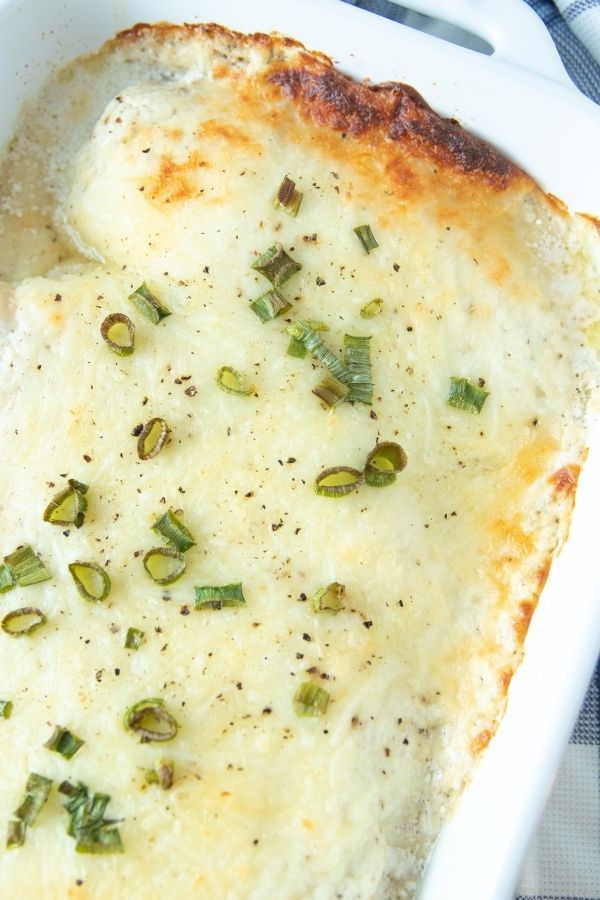 creamy chicken in baking dish topped with greens