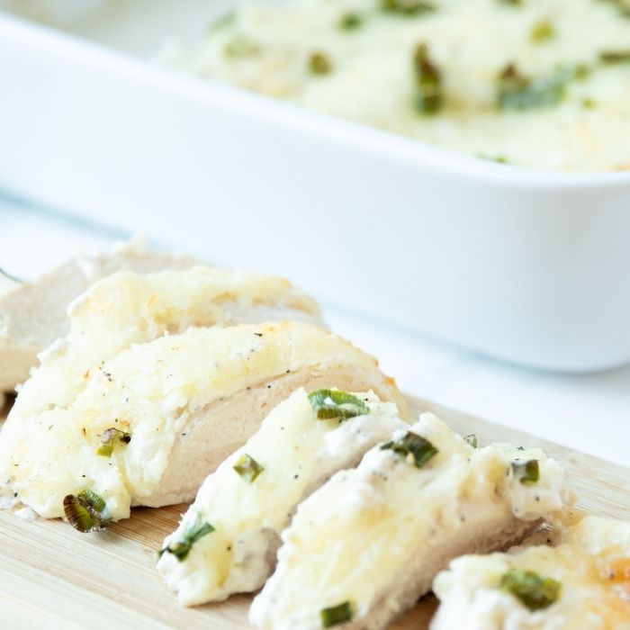 pieces of chicken on wooden cutting board with white pan behind it 