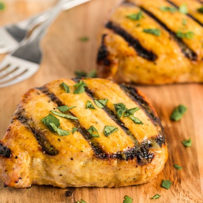 grilled pork chops on wood cutting board