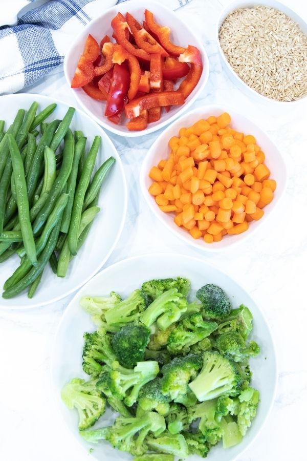 stir fry ingredients on a white table with rice by it 