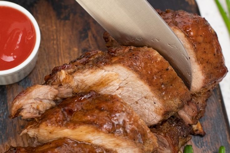 asian flavored ribs on a cutting board with knife