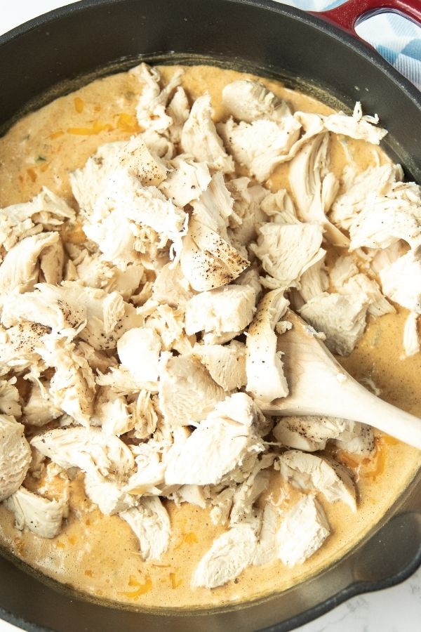chicken mixed in with a creamy sauce in pan
