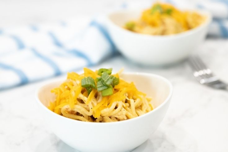 bowl of chicken pasta topped with greens