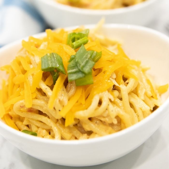 creamy chicken pasta in a bowl topped with green garnish