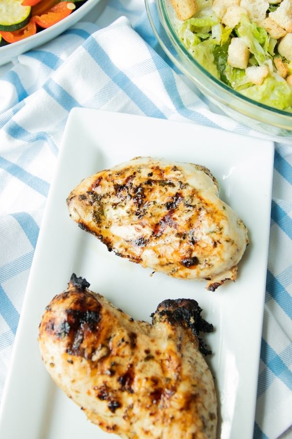 chicken on counter with salad and vegetables by it 