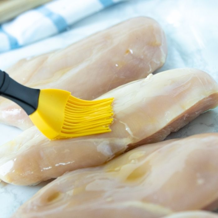 brushing raw chicken with oil 