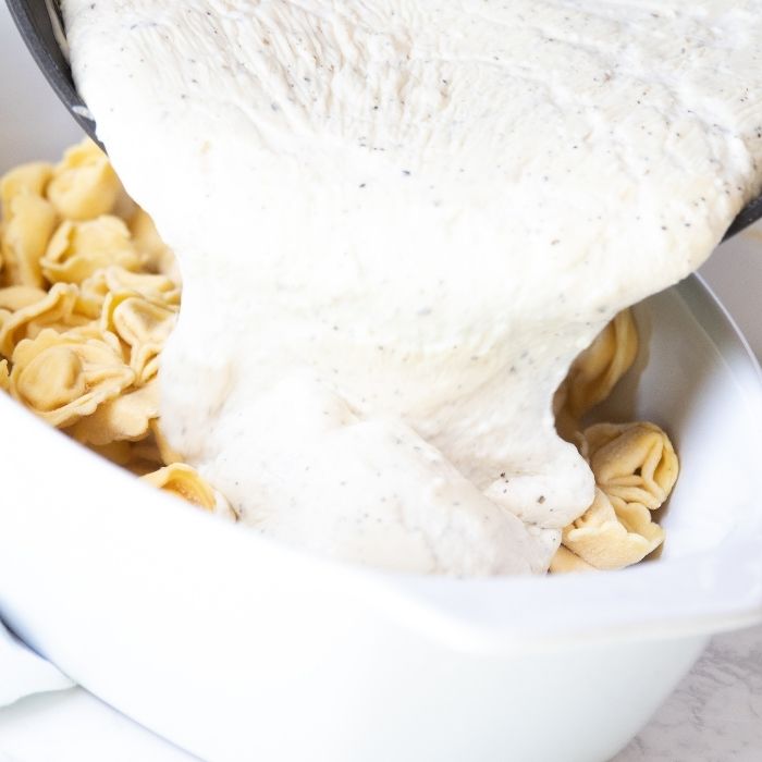 homemade alfredo sauce pouring into pan