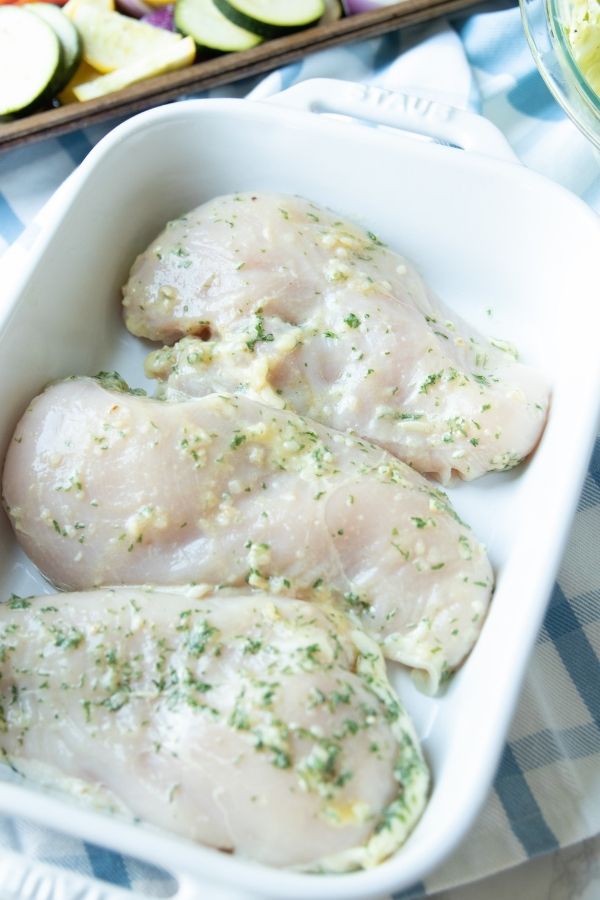 raw chicken seasoned in a white baking dish on table 