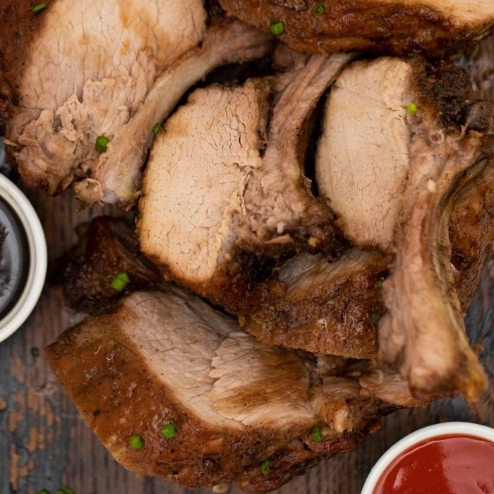 cut up ribs on a cutting board with sauce 