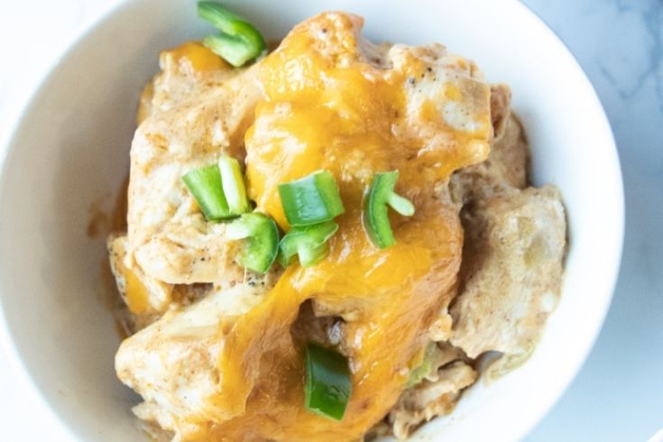 bowl of green chili chicken with cheese and green onions on top